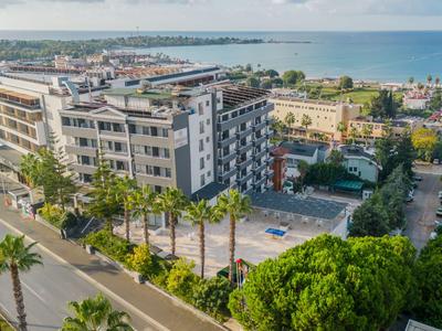 Complexe hôtelier moderne avec plusieurs bâtiments, des palmiers et vue sur la mer en arrière-plan.