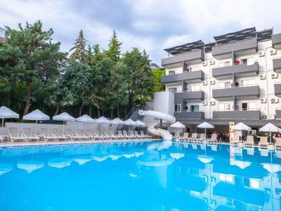 Grande piscine devant un hôtel à plusieurs étages avec transats et parasols.