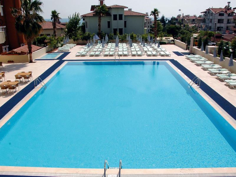 Grande piscina rettangolare con sdraio e ombrelloni in hotel.