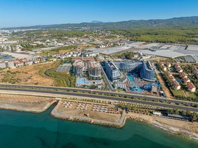 Città costiera con spiaggia, autostrada, aree residenziali e industriali sotto un cielo limpido.
