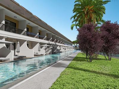 Moderní hotelový komplex s bazénem, zeleným trávníkem a palmami pod jasnou oblohou