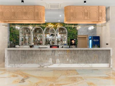 Modern hotel bar with light wood panels, large mirrors, and bright marble counter.