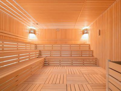 Bright sauna with wooden slatted walls and multi-level benches for relaxation.
