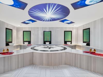 Modern spa room with circular hot tub and six relaxation spots, bright walls.