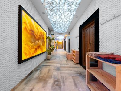 Modern hotel corridor with white brick walls, light marble floor, and decorative ceiling lighting.