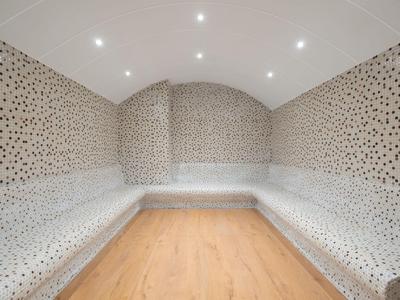 Modern steam room with mosaic tiles and wooden floor in a wellness hotel.