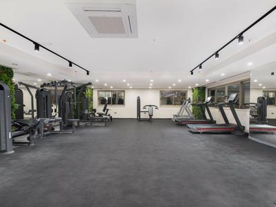 Modern, spacious gym with treadmills, strength machines, and a large mirror wall.