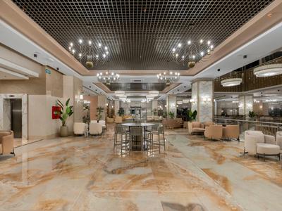 Spacious hotel lobby with shiny marble floor, comfortable seating areas, and modern ceiling lights.