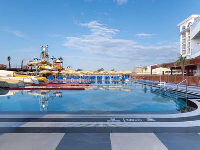 Large outdoor pool with blue loungers and water slides under a blue sky.