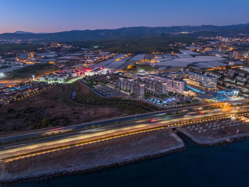 Vista di una città illuminata con strade e acqua al crepuscolo.