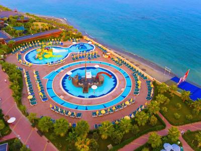 Parcs aquatiques colorés et piscines près de la plage avec chaises longues et sentiers le long de la côte.