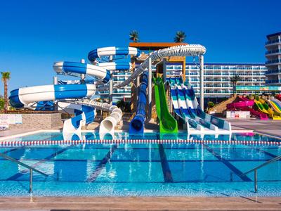 Toboggans aquatiques et piscine d'un hôtel sous un ciel bleu clair.