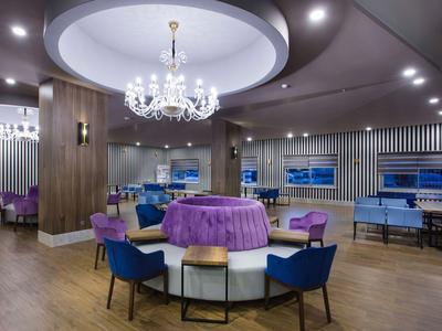 Espace lounge d'hôtel élégant avec lustre, sièges ronds et nappe violette.