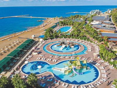 Großer Wasserpark mit mehreren Pools, Liegestühlen, Palmen und direktem Zugang zum Strand.