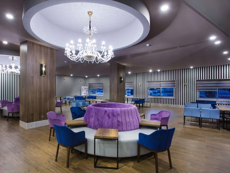 Espace lounge d'hôtel élégant avec lustre, sièges ronds et nappe violette.