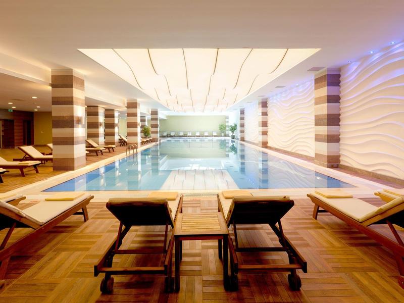 Overdekt zwembad met ligstoelen en warme verlichting in een modern hotelspa.