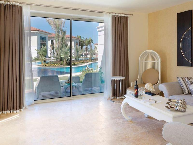 Lichte woonkamer met moderne meubels en grote ramen met uitzicht op balkon en stadsgezicht.