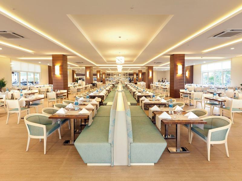 Grote, moderne hotel eetzaal met netjes opgestelde tafels en comfortabele zitplaatsen.