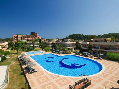 Grande hotel con piscina centrale e sedie a sdraio circostanti sotto un cielo limpido.
