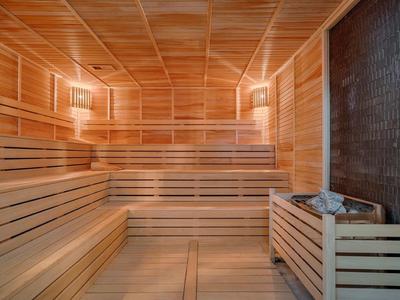 Przestronna sauna z drewnianymi ławkami i piecem na kamienie do relaksu.