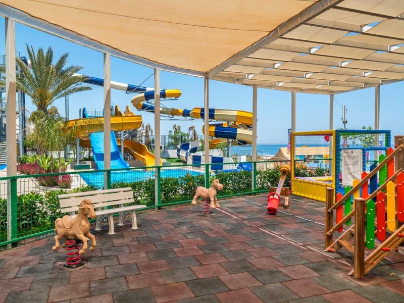 Zewnętrzny plac zabaw z kolorowymi zjeżdżalniami wodnymi i konstrukcjami pod dachem.