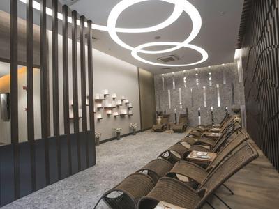 Moderní hotelová čekárna se stylovými židlemi a geometrickým stropním osvětlením