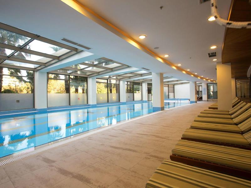 Moderní vnitřní bazén s lehátky a velkými skleněnými stěnami pro denní světlo