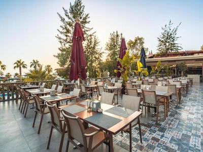 Restaurant en plein air avec tables, chaises et parasols fermés au coucher du soleil.