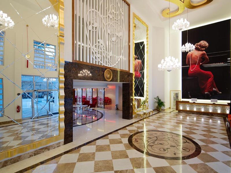 Elegancka lobby hotelowa z żyrandolami, dużym dziełem sztuki i marmurową podłogą.