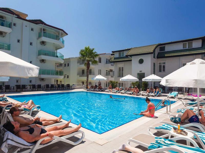 Hotelzwembad met ligbedden en parasols bij zonnig weer.