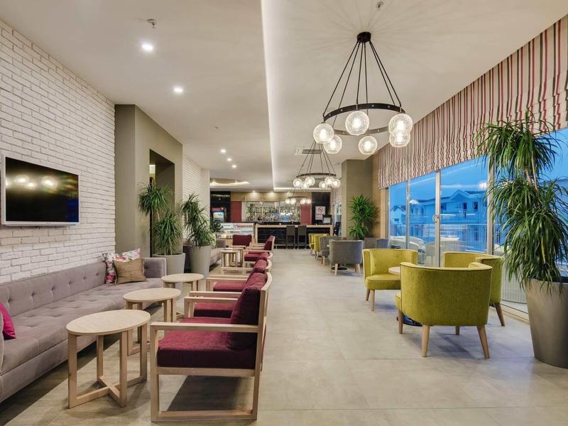 Lichte hotel lounge met moderne zitmeubelen, planten en grote ramen