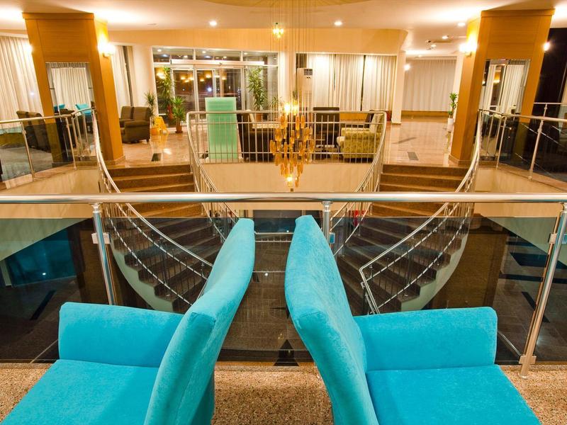 Interno di un hotel con poltrone blu e scala per il piano inferiore con luce calda.