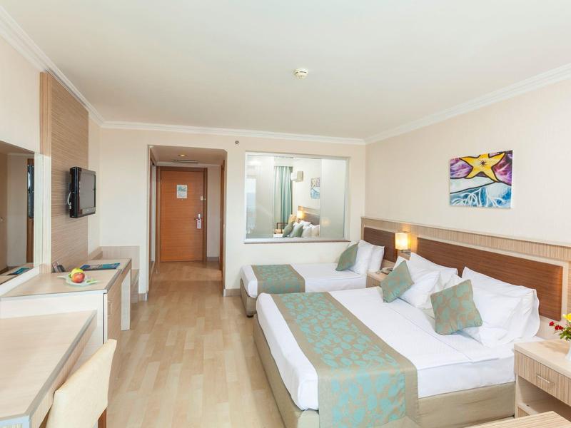 Camera d'hotel moderna con letto matrimoniale, scrivania e zona salotto, luminosa e accogliente.