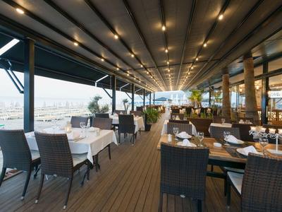 Terraza cubierta de restaurante con mesas, sillas y vista al agua.