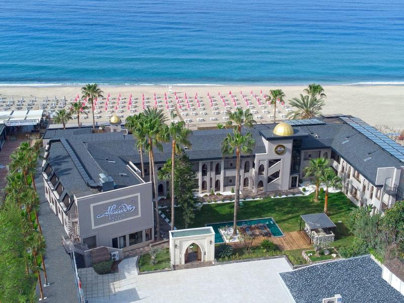 Hotel di lusso con piscina e accesso diretto alla spiaggia, circondato da palme.