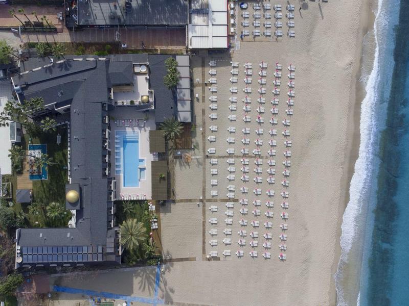 Veduta aerea di un hotel con piscina e numerosi ombrelloni sulla spiaggia vicino al mare