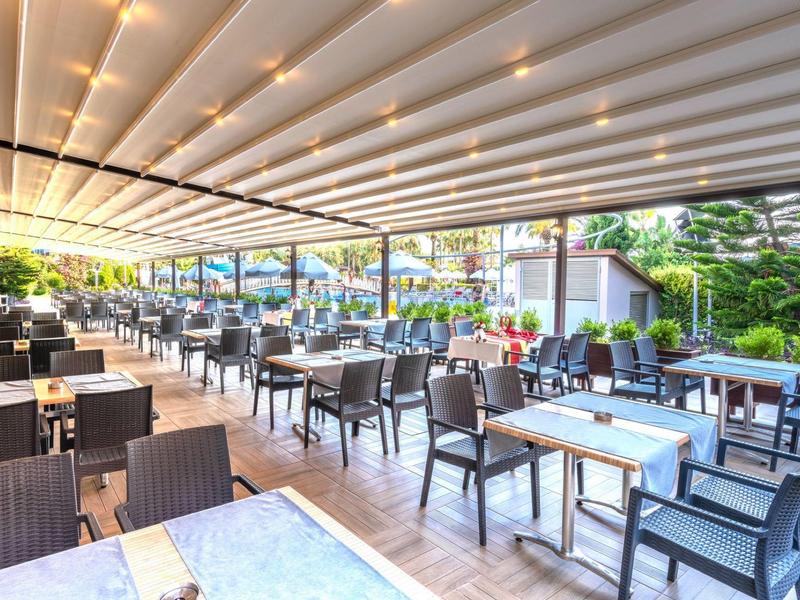 Spacious outdoor dining area with rows of tables and chairs under a white canopy.