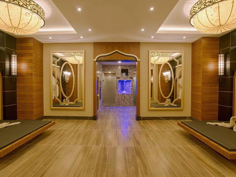 Corridoio elegante dell'hotel con specchi decorativi, lampade e pavimento in legno.