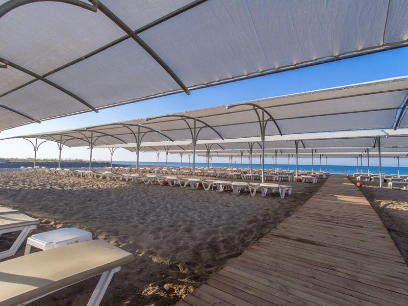 Lettini da spiaggia coperti su una spiaggia sabbiosa con vista sul mare sotto un cielo azzurro