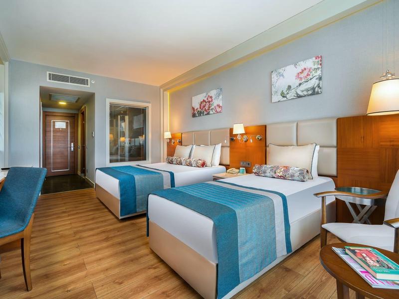 Camera d'hotel moderna con due letti, pavimento in legno e decorazioni murali luminose.