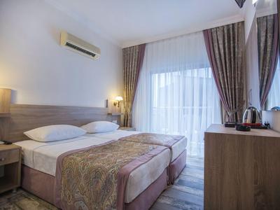 Chambre d'hôtel confortable avec lit double, climatisation et balcon avec rideaux.