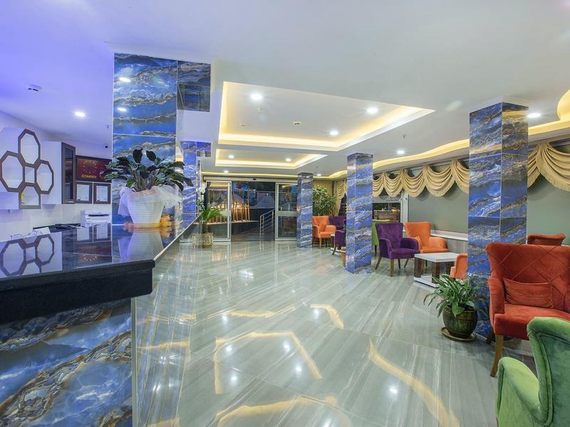 Ampia hall dell'hotel con pavimento in marmo lucido, colonne e illuminazione moderna.