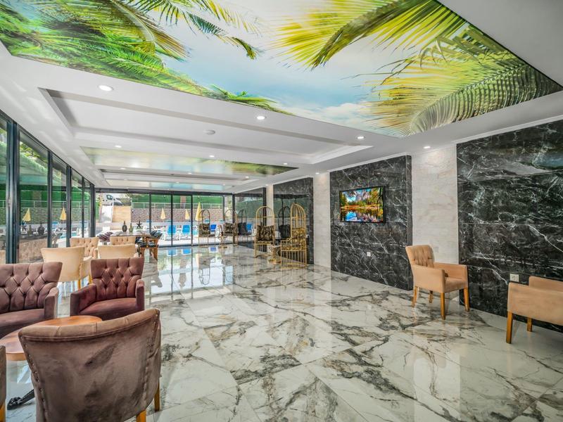 Luxurious hotel lobby with marble flooring, comfortable chairs, and a ceiling painted with palm motifs.