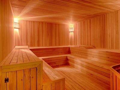 Interno accogliente di una sauna in legno con panche a gradini e illuminazione soffusa.