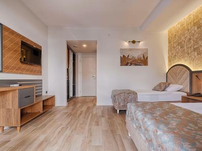 Helles Hotelzimmer mit zwei Betten, Holzboden und moderner Einrichtung.