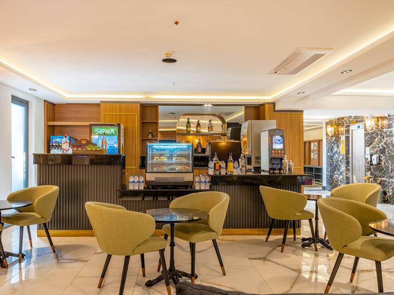 Sala colazione moderna con tavoli rotondi e sedie verdi.