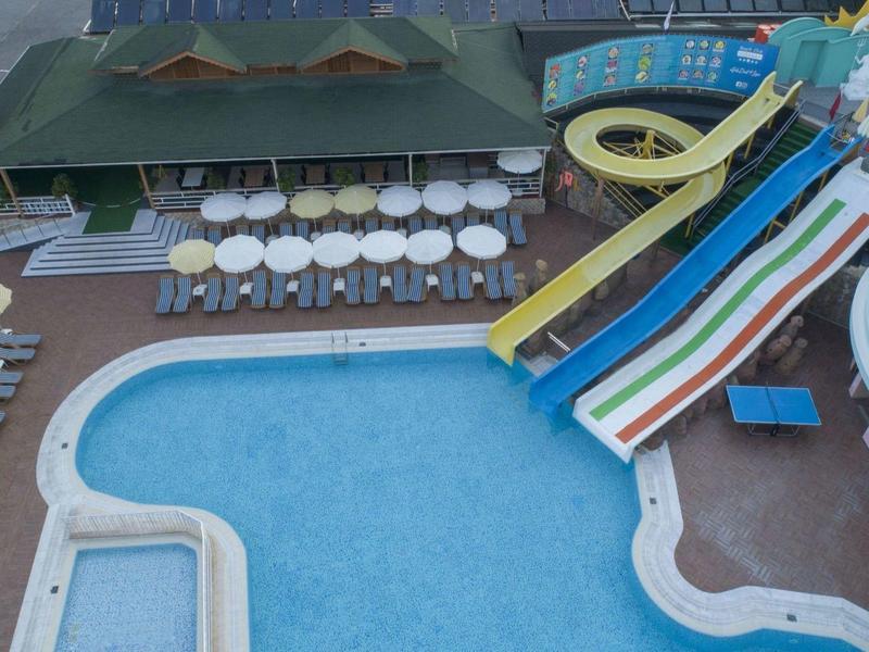 Vista aerea di una piscina con scivoli colorati e ombrelloni bianchi intorno.