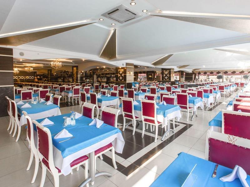 Ampia sala da pranzo con tavoli blu e sedie rosse disposti ordinatamente.