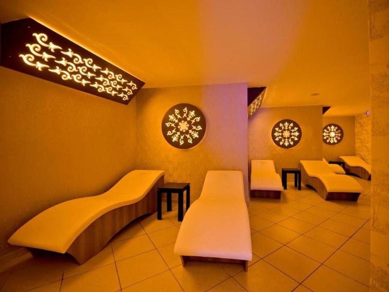 Sala relax illuminata gialla con chaise longue curve e pareti decorate.