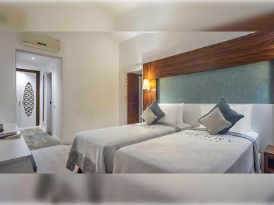 Chambre d'hôtel moderne avec deux lits simples, lampes de chevet et télévision à écran plat au mur.